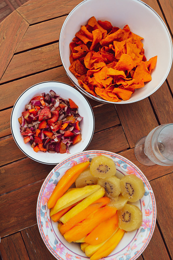 Mangoes, kiwi fruit, salsa, and chips snacks by the swimming pool on a sunshiny day at home