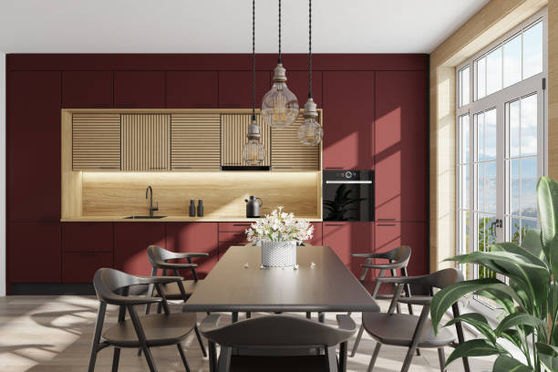 istock Dark red and light wood Modern Scandinavian kitchen with large dining table and chairs. Large windows. Open space kitchen concept. Summer scene. 1313916711