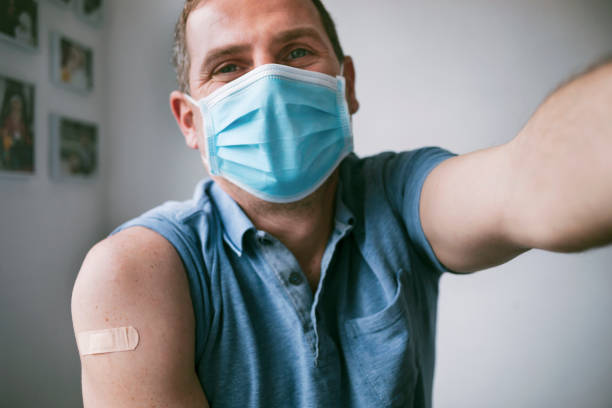 Man wearing protective face mask taking a selfie after vaccination against Covid-19