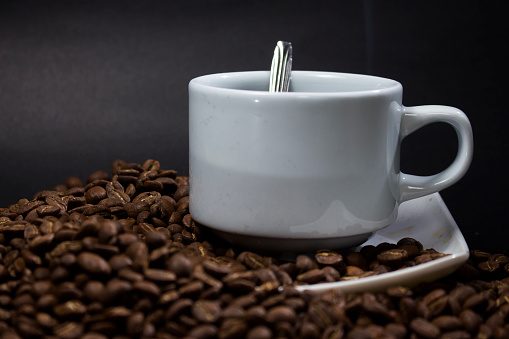 Coffee cup and coffee beans on black background