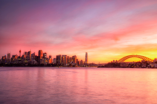Crimson bright sunset over Sydney city CBD landmarks across Harbour with the Harbour bridge.