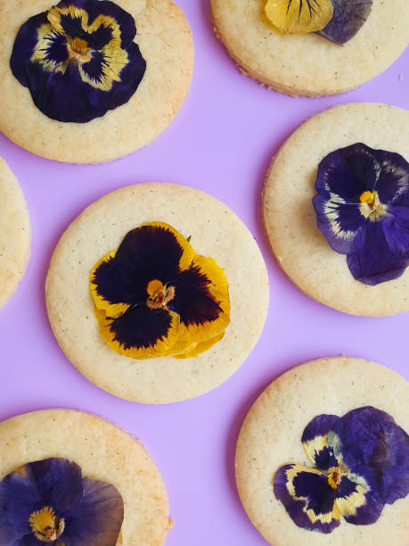 okrągłe ciasteczka cukrowe z bratkami na fioletowym tle płaskie leżały - sugar flowers zdjęcia i obrazy z banku zdjęć