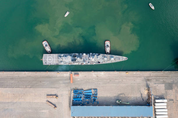Aerial view of military war ship approaching to a commercial port. Aerial view of military war ship approaching to a commercial port. Navy War Ship. jetty aerial stock pictures, royalty-free photos & images
