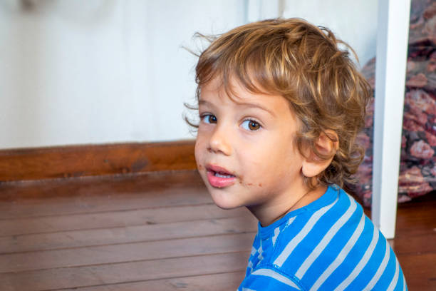 Detail of a cute, redhead, blue-eyed boy sitting in a green pushchair on a sunny day