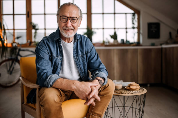 verticale de l’homme aîné s’asseyant dans la présidence - homme 65 ans photos et images de collection