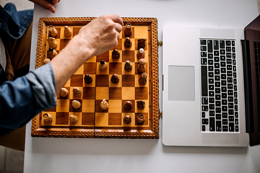 Close up of unrecognisable mature man holding chess piece and making a move