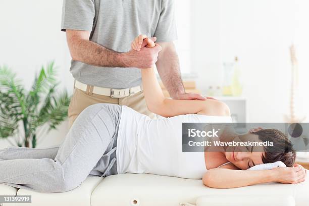 Chiropractor Stretches Female Customers Arm Stock Photo - Download Image Now - Active Lifestyle, Adult, Adults Only