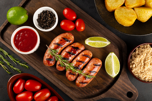Grilled barbecue sausages on wooden background.