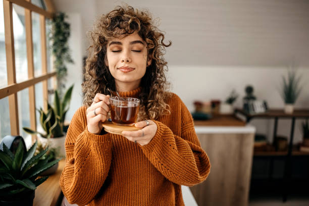 retrato de una joven hermosa que toma un té en su apartamento - bebida caliente fotografías e imágenes de stock