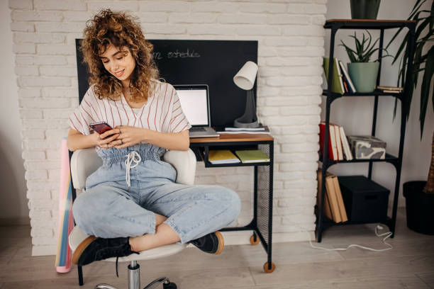 istock Young beautiful woman using her mobile phone in her small home office 1313934143
