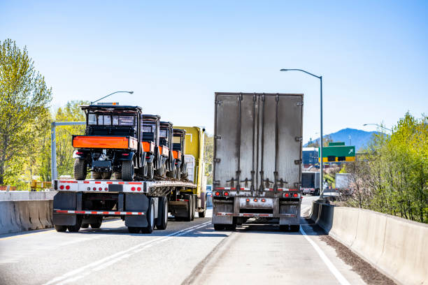 istock Two loaded big rig semi trucks with different semi trailers running side by side on the narrow two line highway intersection at sunny day 1313940405