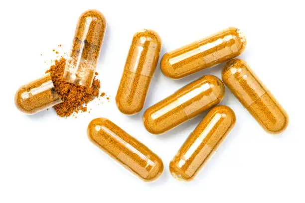 Closeup turmeric herbal powder capsules isolated on white background. Top view. Flat lay.