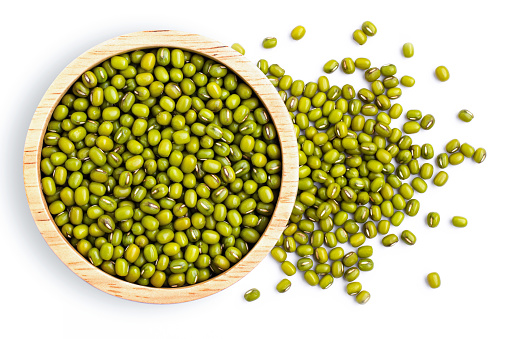 Green mung beans in wooden bowl isolated on white background. Top view. Flatlay.