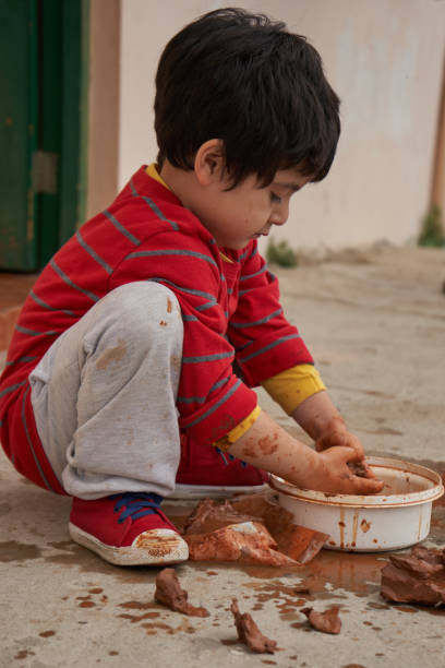istock Child kneeling and very concentrated makes figures with clay, molding clay. Clay session 1313946685