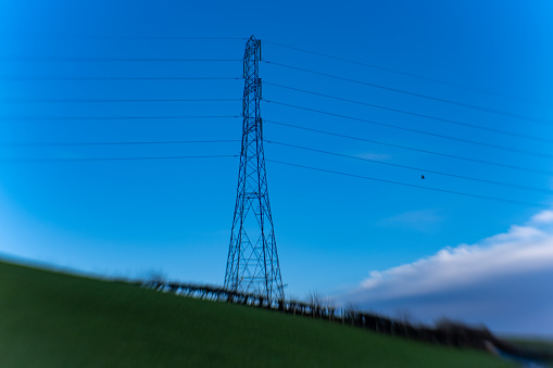 High voltage electricity power cables passing across English countryside. Taken with lensbaby lens to give intentional blur effect
