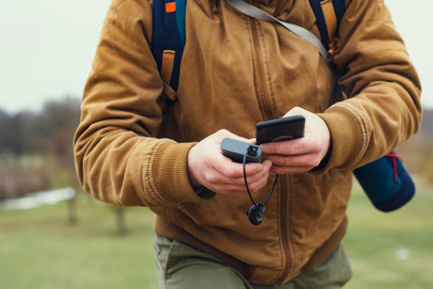 Tourist is holding a portable charger with a smartphone in his hand. Man on a background of nature with greens. Tourist is holding a portable charger with a smartphone in his hand. Man on a background of nature with greens usb port photos stock pictures, royalty-free photos & images