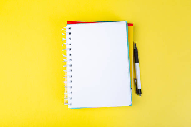 istock open spiral notepad on a yellow background with a pen. top view, stack of notepad with blank sheet. school concept, businessman work desk. 1313958531