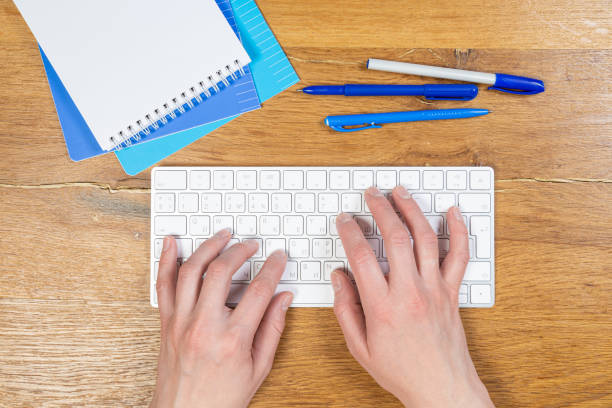 istock An image of a woman's hand is typing on a white keyboard on a wooden table. Selective focus 1313959409