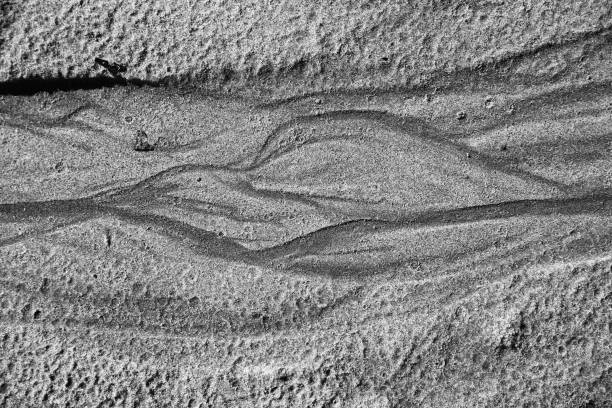 patterns on sandy beach after high and low tide on the ocean, black and white abstract sand background