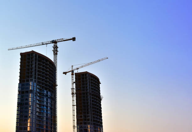 istock Tower cranes in action at construction site on blue sky background. A crane the conctruct the high-rise building 1313964879