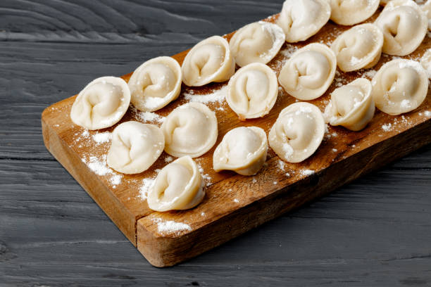 Raw meat dumplings on wooden board on table Raw meat dumplings on wooden board on table close up russian pelmeni stock pictures, royalty-free photos & images