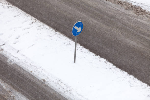 istock Blue sign with white arrow on road during winter 1313966156