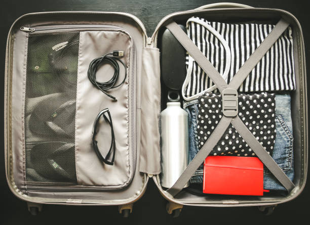 istock Open suitcase full of clothes isolated on black background 1313967497