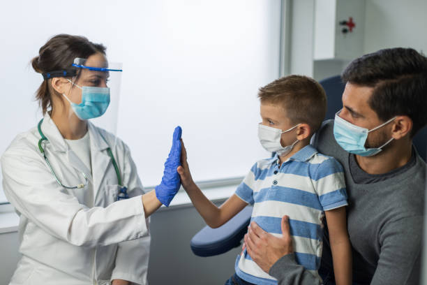 junge in der arztpraxis - nurse high five mask stock-fotos und bilder