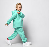 Portrait of a little stylish boy in a warm sports suit on a gray background