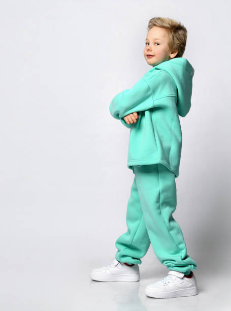 istock Happy cute blond boy in a warm turquoise suit on a gray background 1313973444