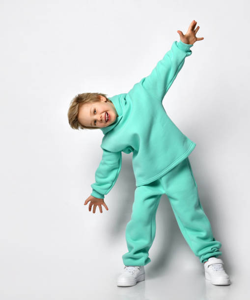 istock Happy cute blond boy in a warm turquoise suit on a gray background 1313973813
