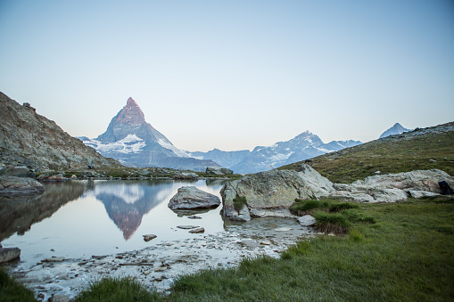 Sunlight on the top of the peak , reflection on water surface.\nValais, Switzerland