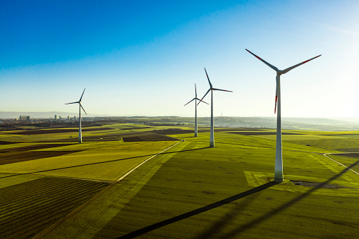 Aerial View of Wind Turbines and Agriculture Field  in the Early Morning at Sunrise.
