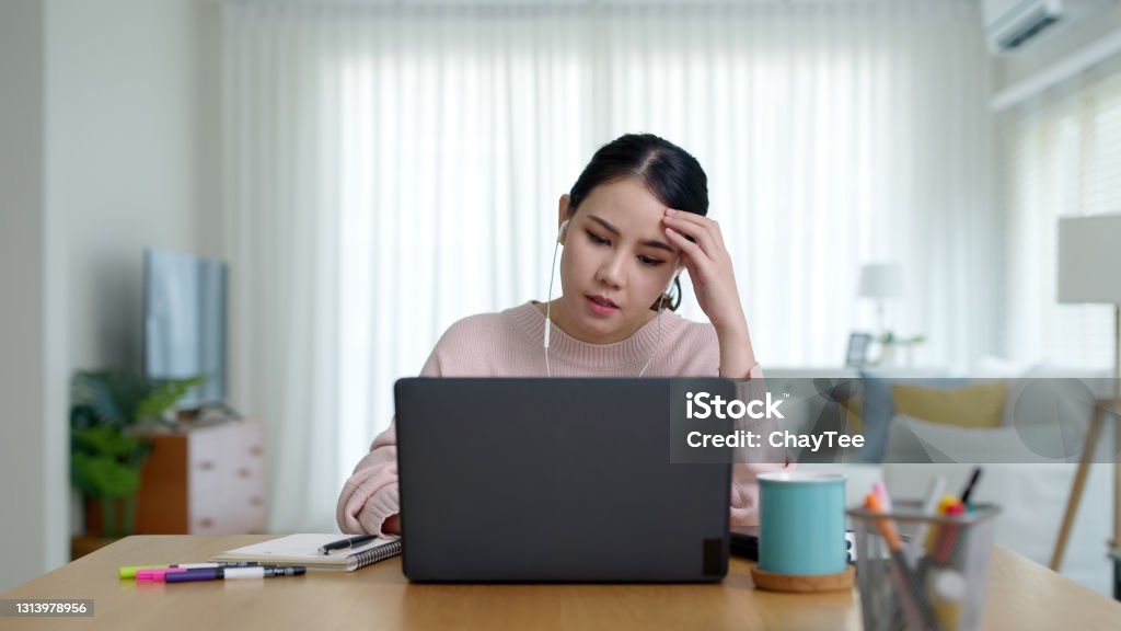 Young asian woman employee work from home using computer notebook videocall meeting conference angry annoy with low poor unreliable internet wifi connection problem issue outage. Offline - Technology Stock Photo