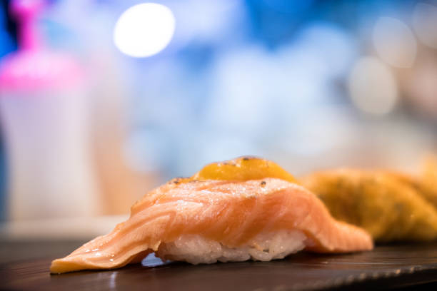 istock Aburi burn salmon sushi. Garnished with sauce. served on black plate. Selective focus 1313978959