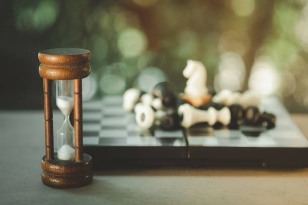 Hourglass with blur background with chess on wood table