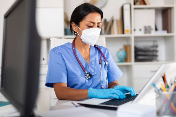 istock General practitioner woman in mask working on laptop 1313980362