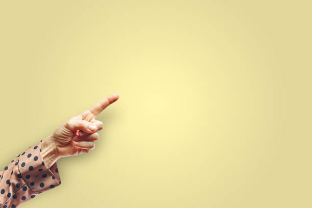 Woman arm making pointing gesture with hand isolated on yellow background. Gesture concept