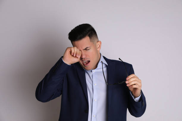 istock Handsome tired businessman yawning on light grey background 1313981164