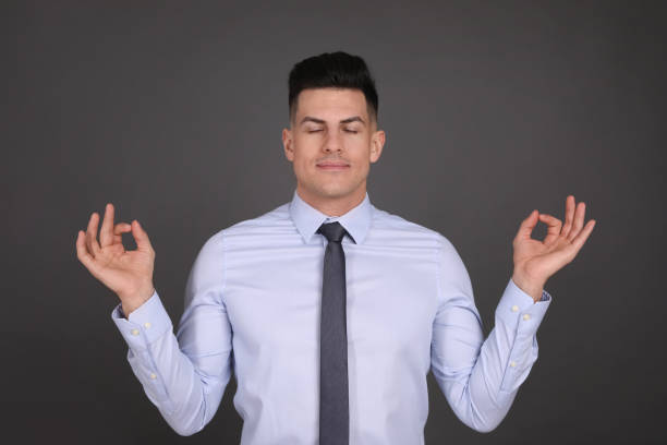 istock Businessman meditating on dark grey background. Personality concept 1313981820