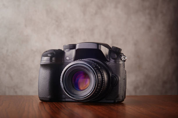 istock Digital mirrorless professional camera on wooden table with concrete wall as a background 1313983254
