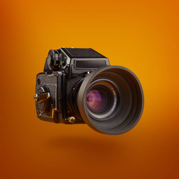 cámara de película de formato medio que fluye sobre un fondo de color naranja - medium format camera fotos fotografías e imágenes de stock