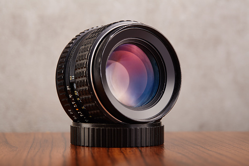 Digital camera lens, DSLR camera lens on wooden table and concrete wall as a background