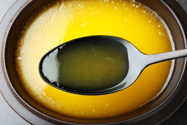 Spoon of clarified butter over bowl, closeup Spoon of clarified butter over bowl, closeup clarified butter stock pictures, royalty-free photos & images