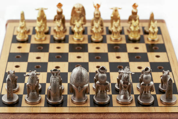 istock Chess board with placed chess pieces stylized as Egyptian gods. Focus on silver pieces 1313990528