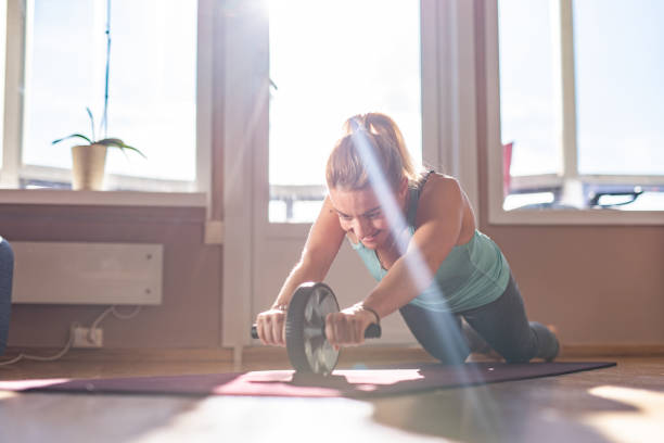Sports woman is doing ab roller exercise