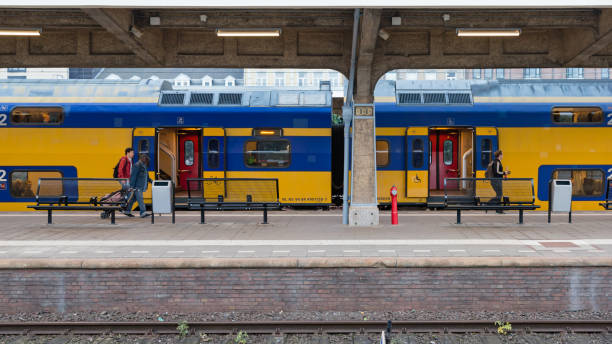 reizigers in en naast een gele ns intercity op station maastricht - ns stockfoto's en -beelden