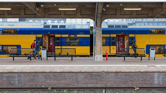 Maastricht, Limburg, Netherlands, september 23rd 2016, passengers walking on the platform at Maastricht railway station next to a yellow Nederlandse Spoorwegen (NS) Intercity train with its doors still opened, other commuters have already boarded and are now waiting for the train to leave he station