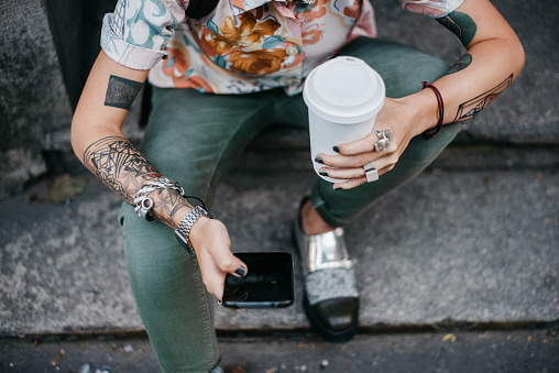Trendy woman holding paper coffee cup and a phone