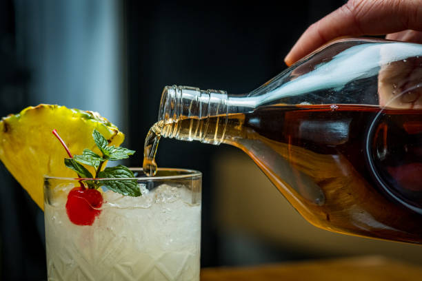 close-up of pouring rum into cocktail drink - transparent holding glass focus on foreground imagens e fotografias de stock